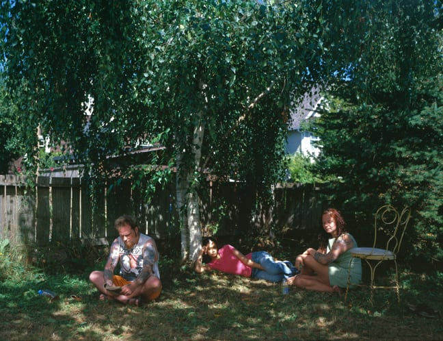A photo of a man, a women and a child in the backyard of a park.