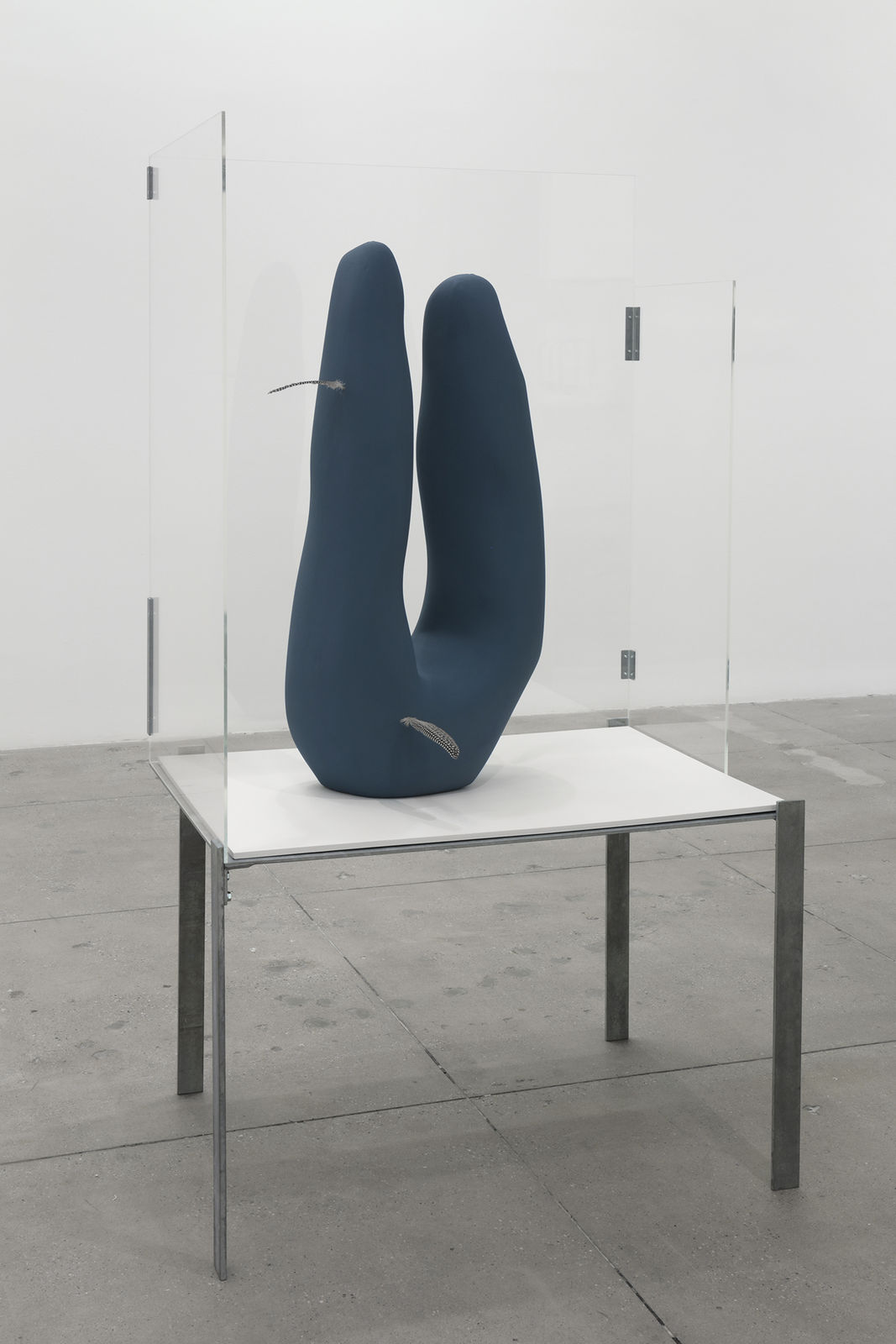 A blue abstract sculpture on a table with three glass walls
