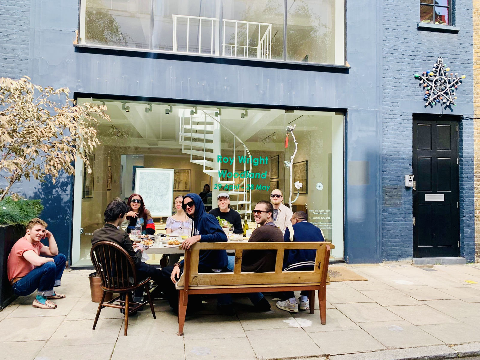 A group of people enjoying a meal around a table in-front of the Rebecca Hossack Art Gallery.