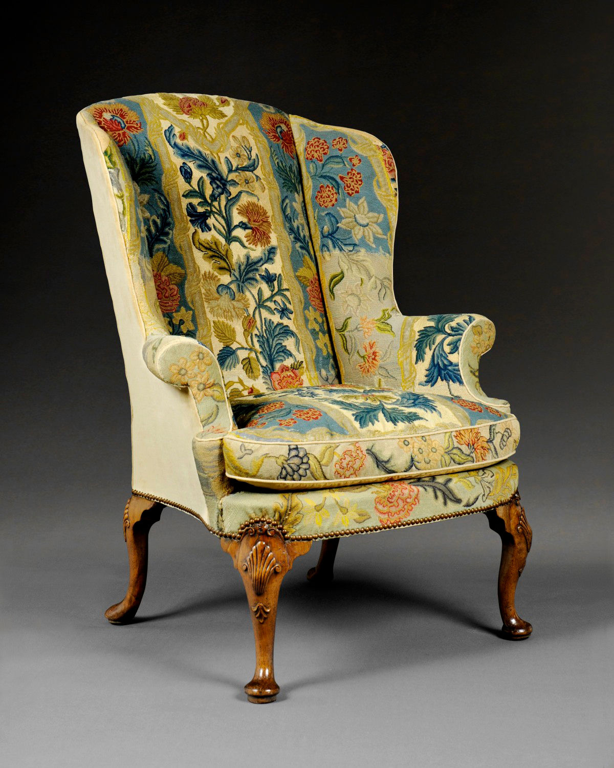 AN EXCEPTIONAL GEORGE I CARVED WALNUT AND NEEDLEWORK WING CHAIR , ENGLISH, CIRCA 1725