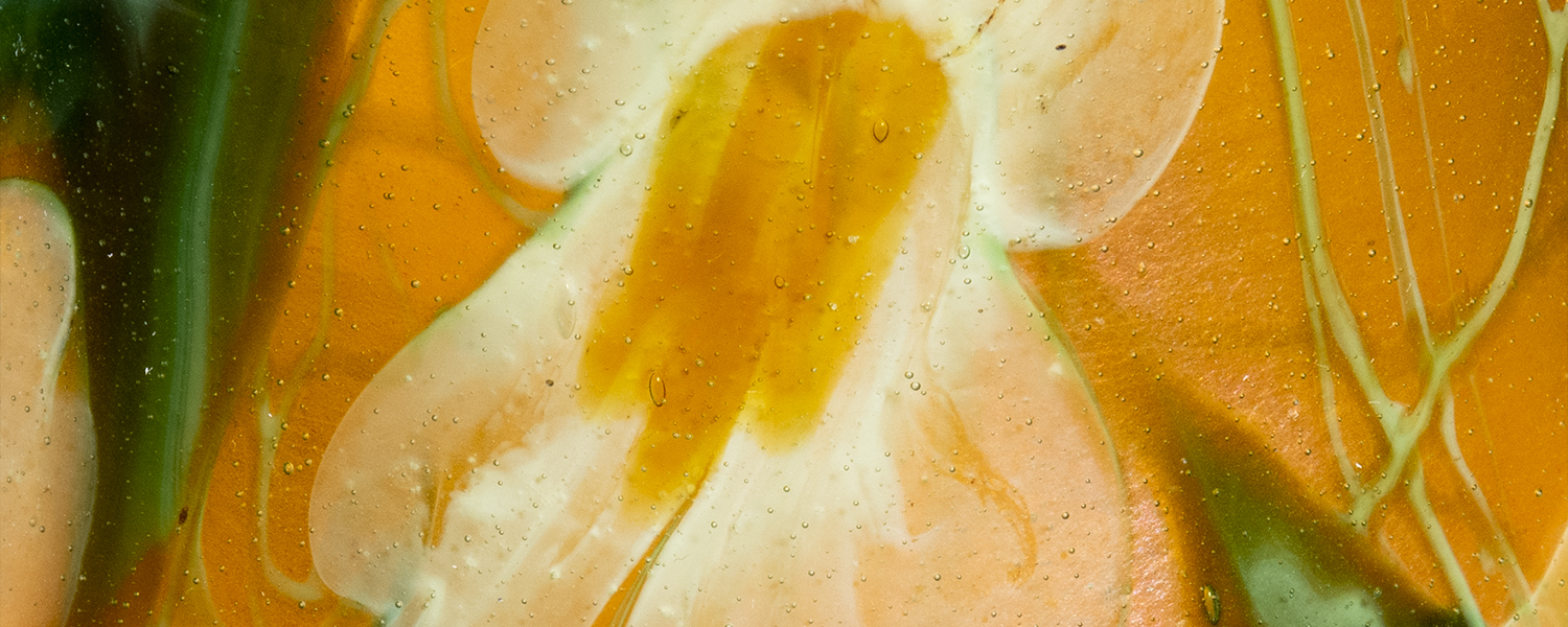 a detail shot of an authentic tiffany favrile glass paperweight vase, depicting white flowers against an iridescent amber background with pointed green leaves and swirling thin green vines