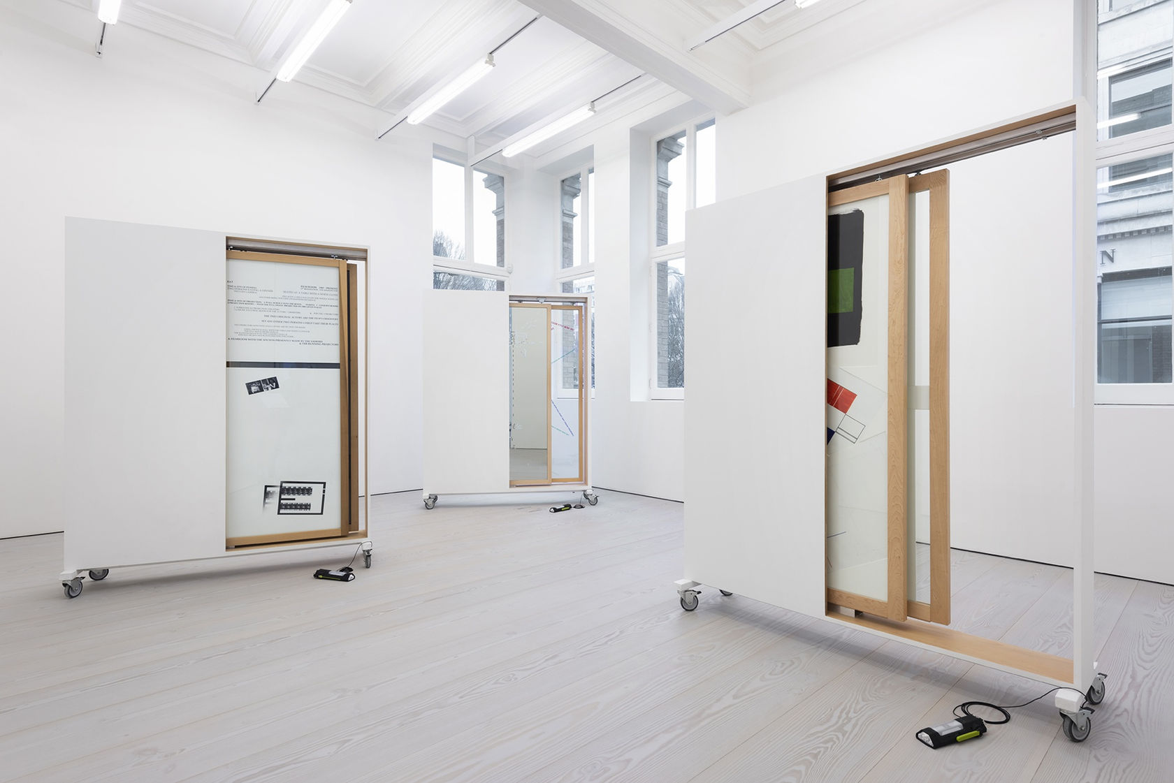 3 structures on wheels contain sliding doors displaying drawings.