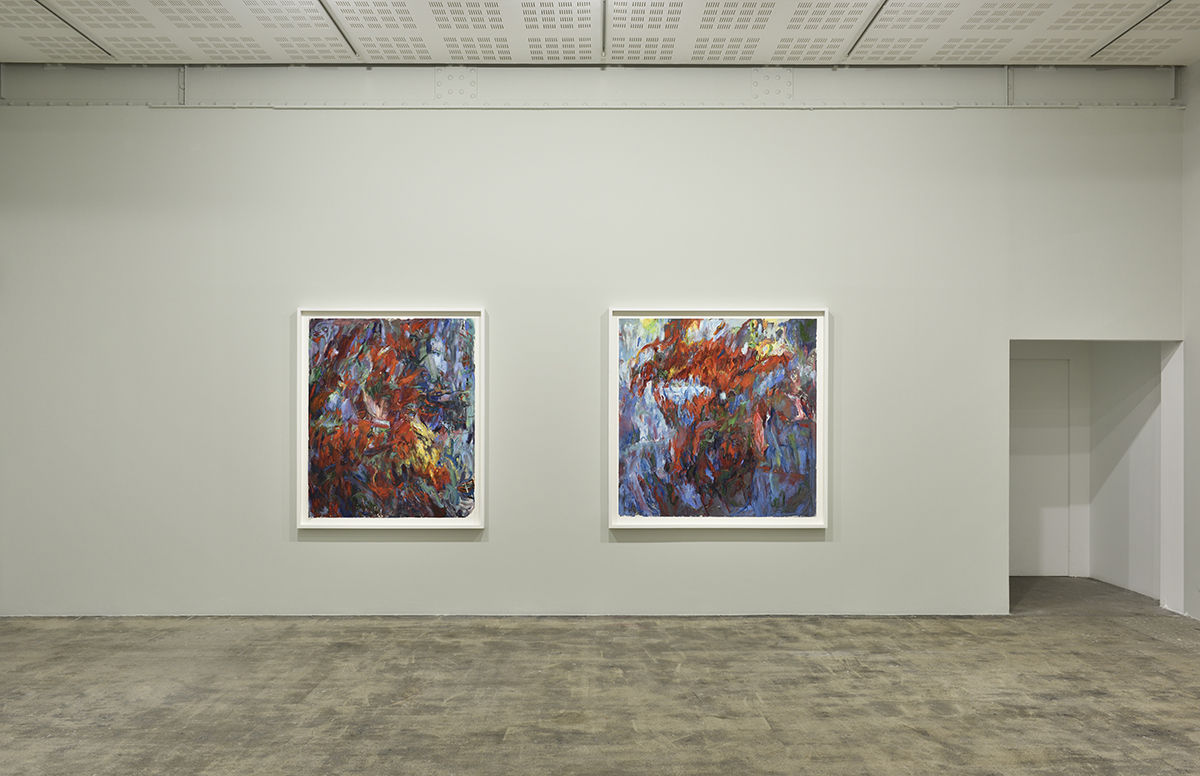 2 framed abstract paintings hung side by side on a beige wall. There is a door on the right. 