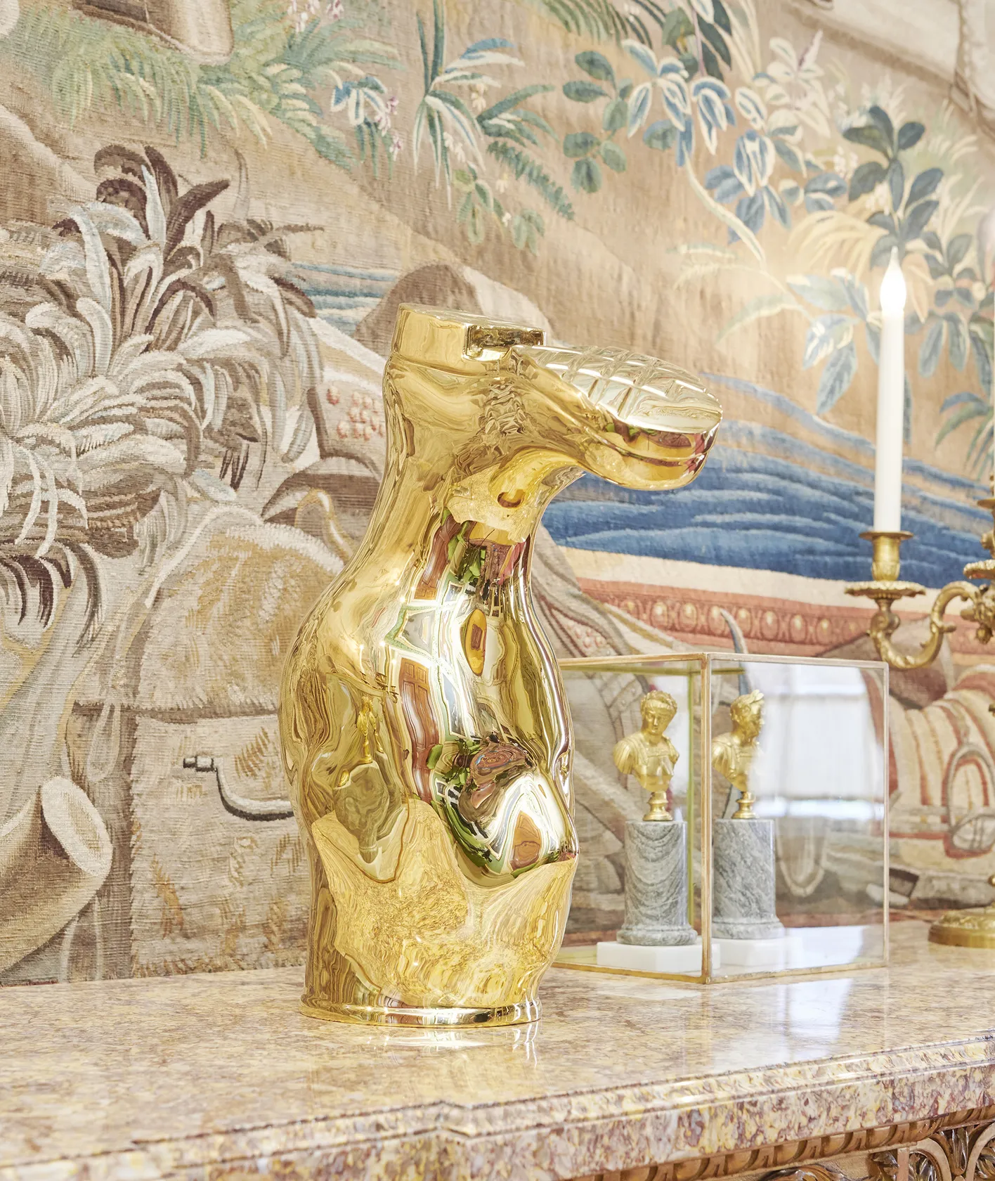 Sculpture of an upside down gold boot on a marble shelf. 