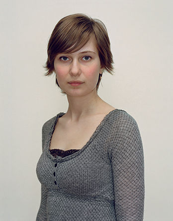 A Rineke Dijkstra portrait of a woman in a gray shirt with short hair.