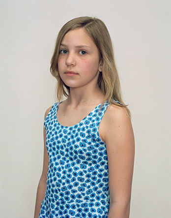 A Rineke Dijkstra portrait of a girl in a blue polka dot tank top.