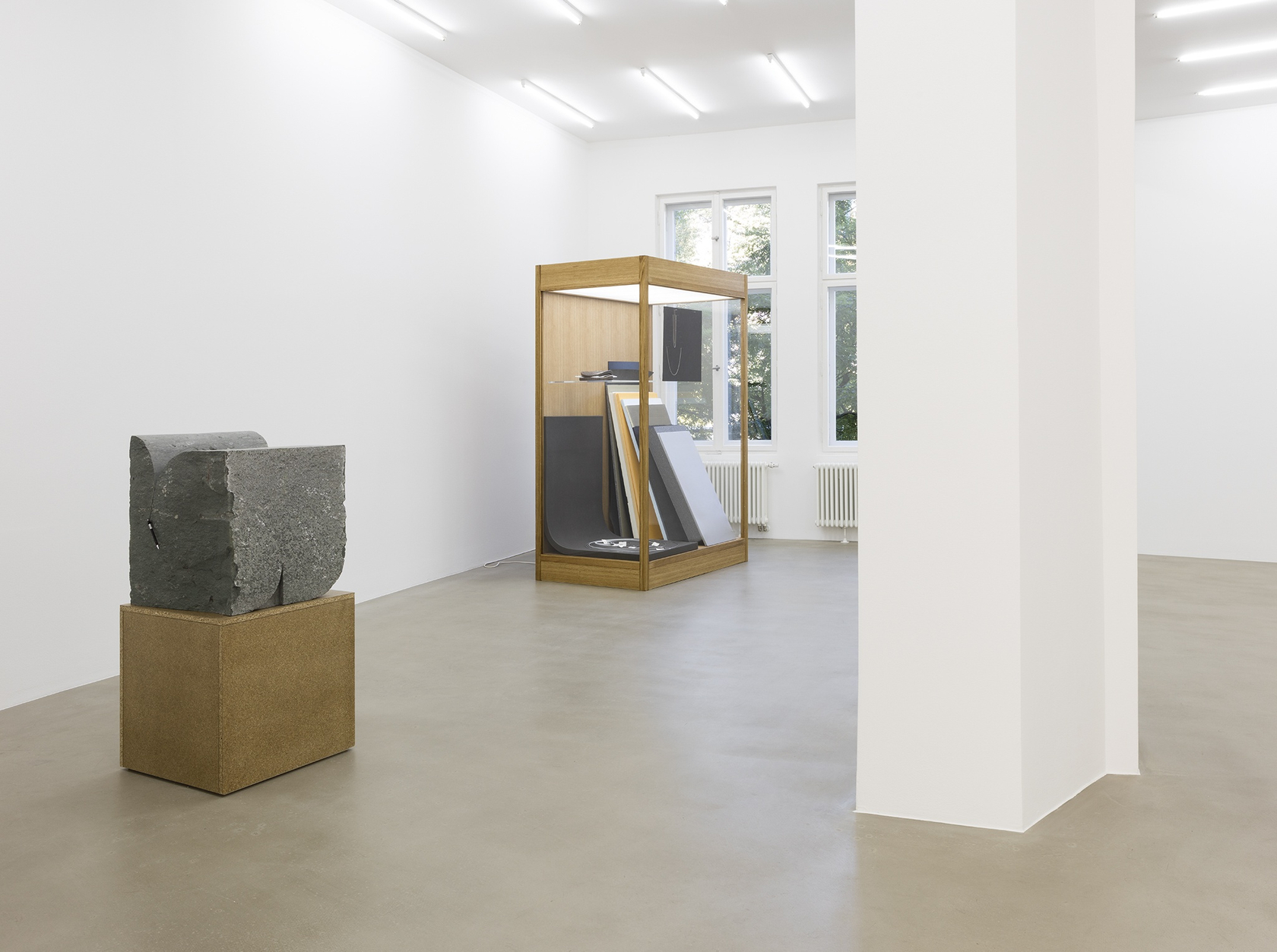 I collate, I convey, I comply (01), 2015 (left) Green Anröchter stone, chipboard plinth, assorted objects The sculpture’s combination of...