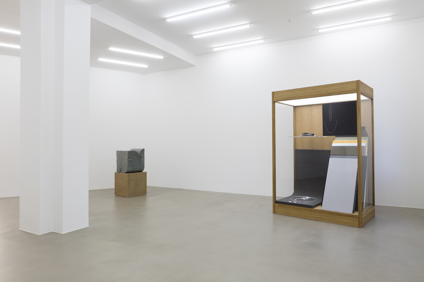 I collate, I convey, I comply (01), 2015 (left) Green Anröchter stone, chipboard plinth, assorted objects The sculpture’s combination of...