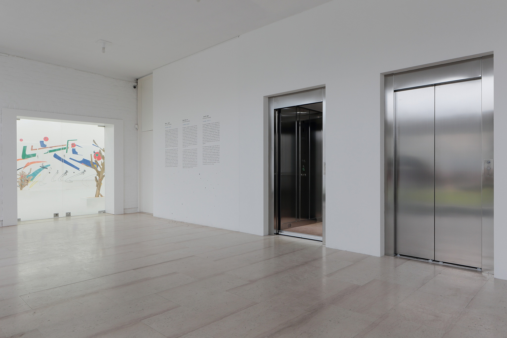 Entrance hall of the museum with locked glass doors to the left. The two elevator doors were added, one is...