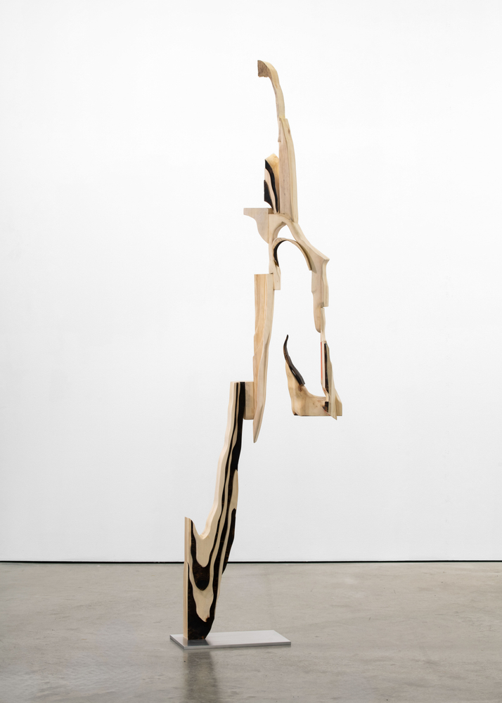 A freestanding sculpture by David Armstrong Six made of wood carved into an abstracted geometric form.