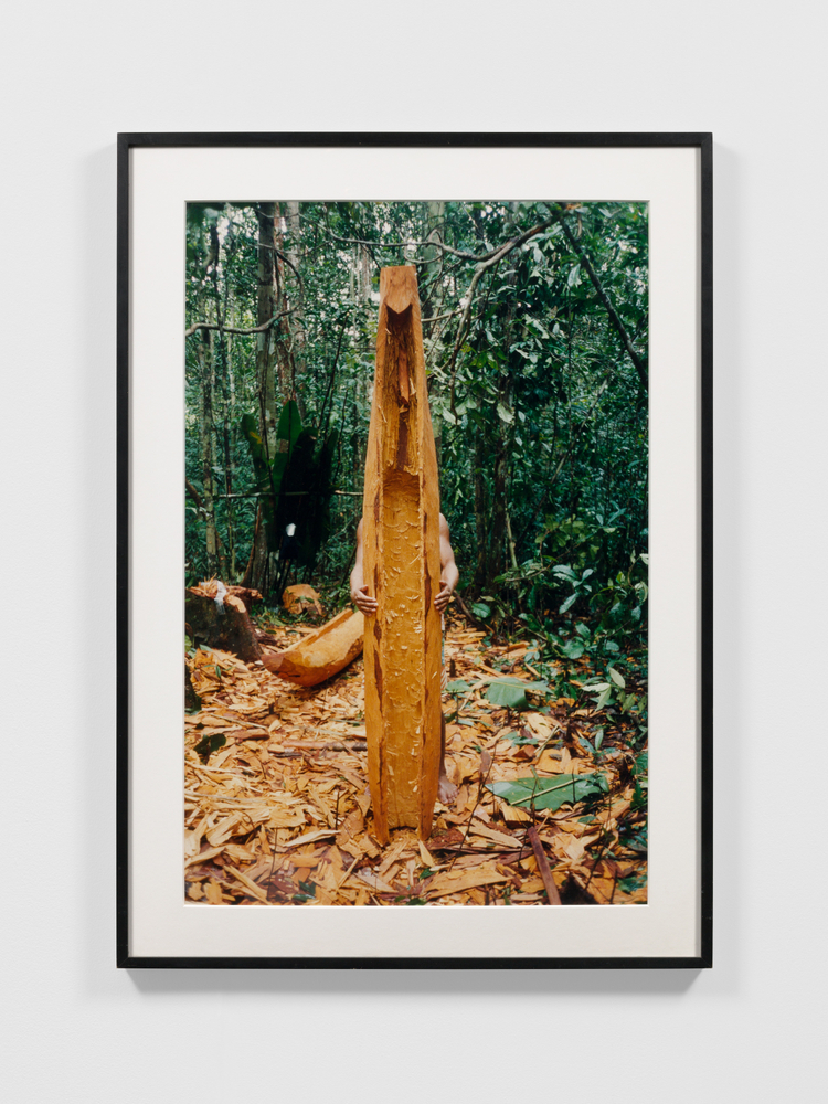 Photograph of a person holding a canoe in front of their body in a forest