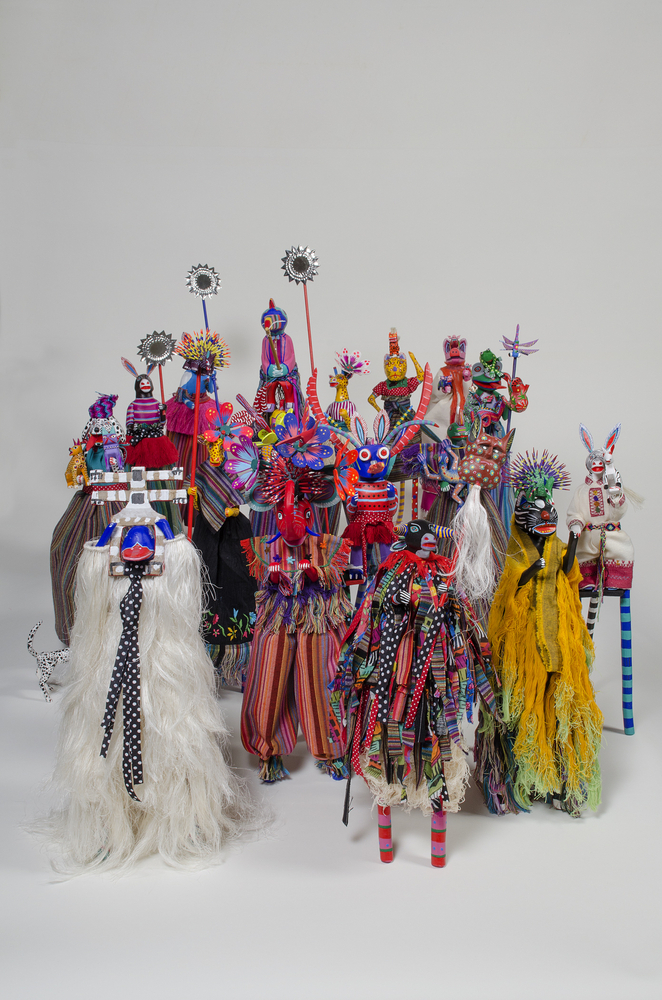 Work depicting a group of colorful doll-like sculptures wearing elaborate costumes