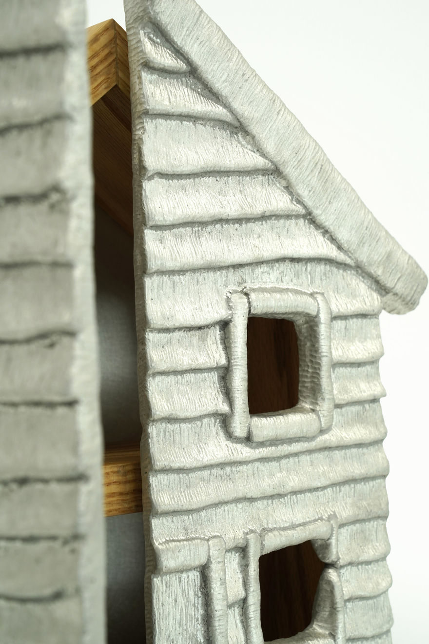 Wooden cabinet shaped like a house with metal cast on the front