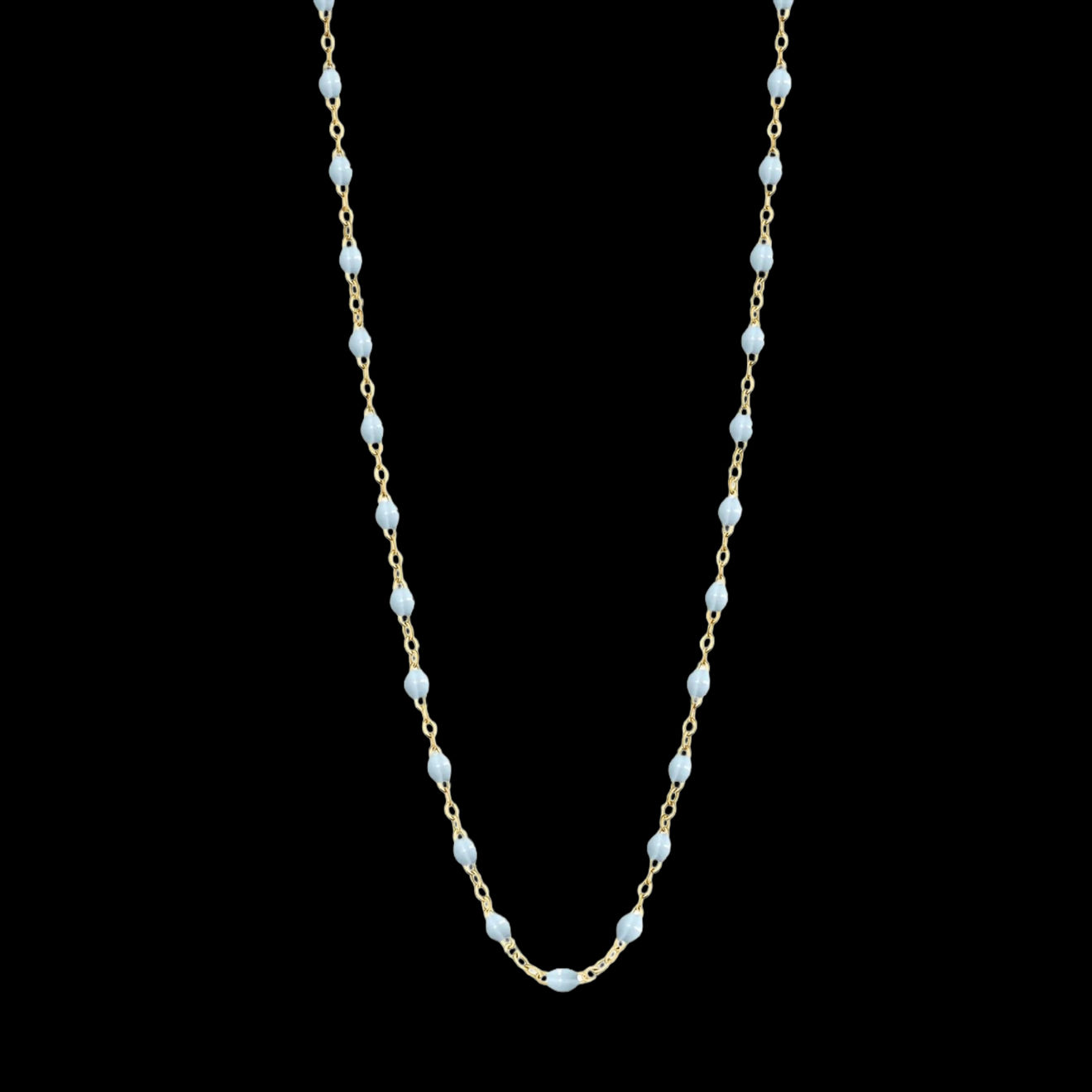 A delicate 18k yellow gold chain necklace featuring evenly spaced small baby blue resin beads, arranged in a gentle U-shape by Fringe Gallery studio jeweler Gigi Clozeau.