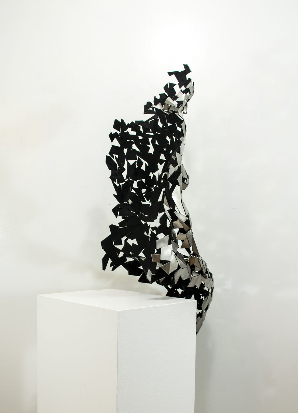 Stainless steel sculpture of a person sitting upright by slate gray gallery artist David Davis