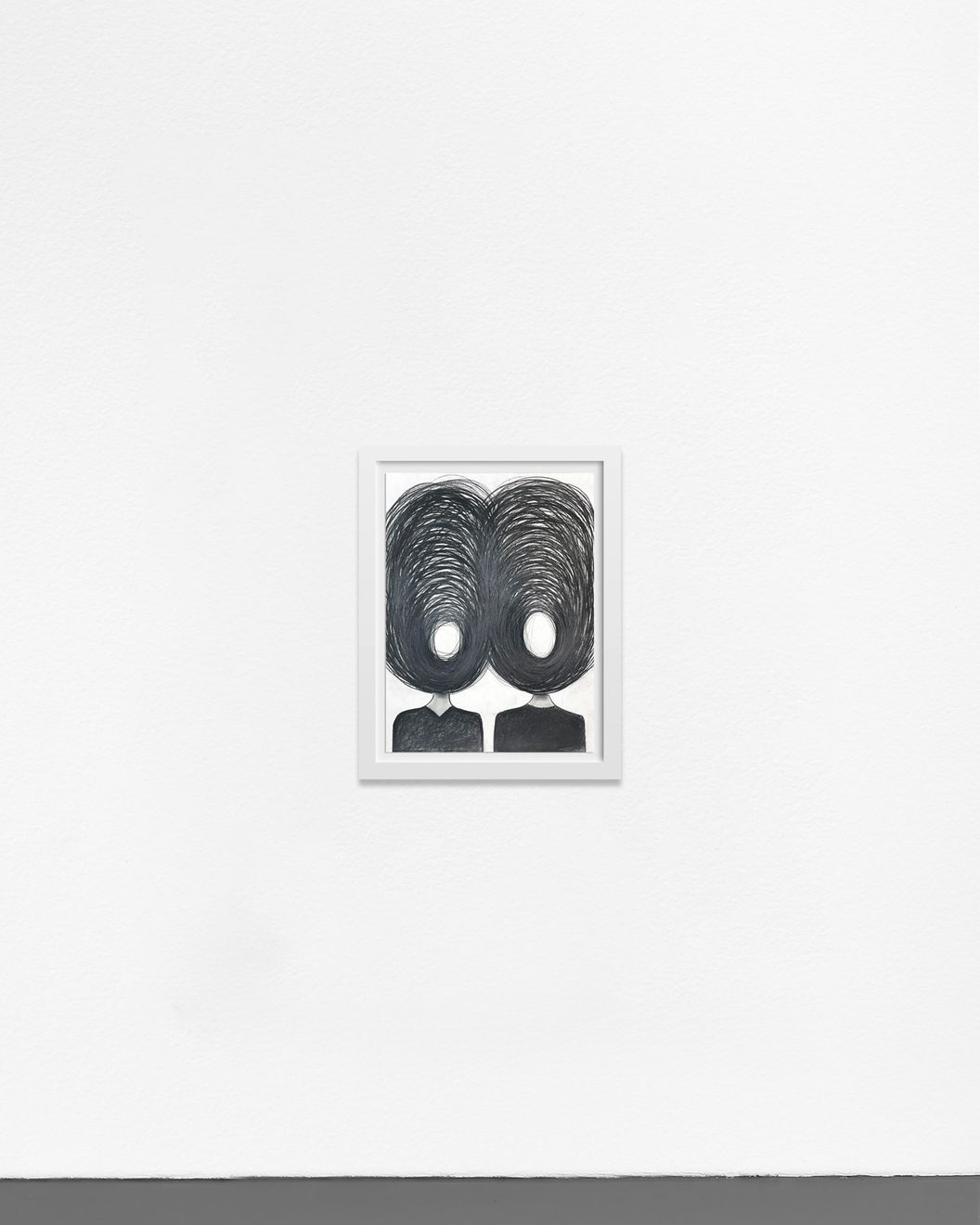 Ted Collier work on paper with two figures and chaotic vicious circle heads in charcoal on white background framed in a white frame hanging on a white wall