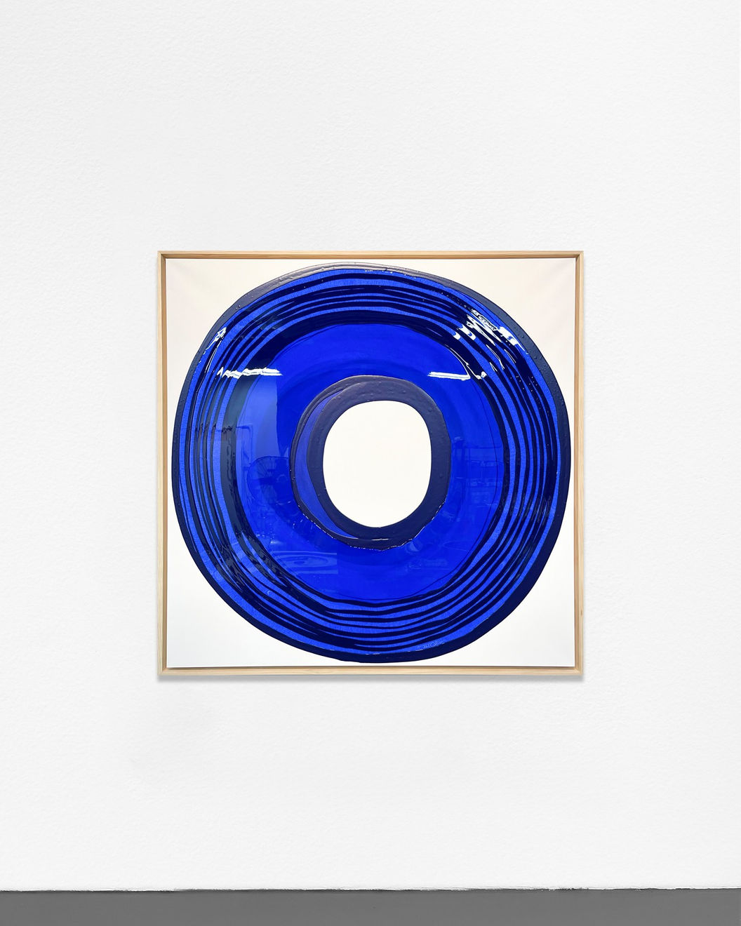 Ted Collier Circle Series painting with blue circle coated in resin on a white canvas hanging on a white wall
