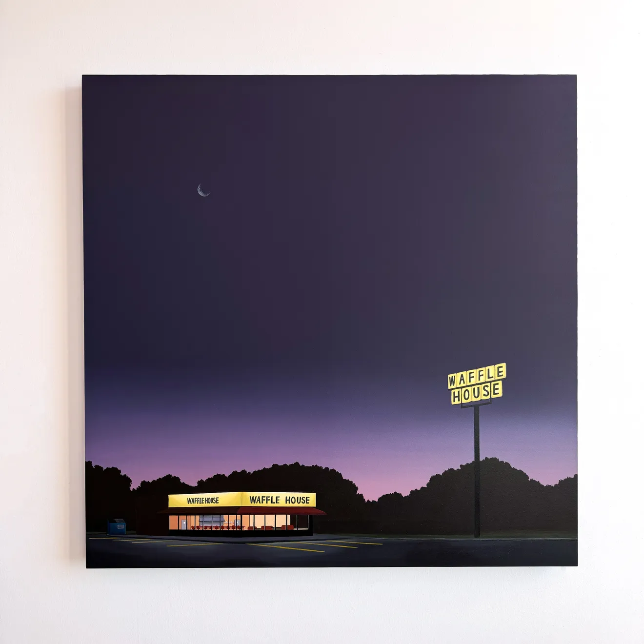 Kristin Moore Moonrise Over Waffle House painting on a white wall featuring a glowing roadside diner at night beneath a deep purple sky with a crescent moon and illuminated Waffle House signage.