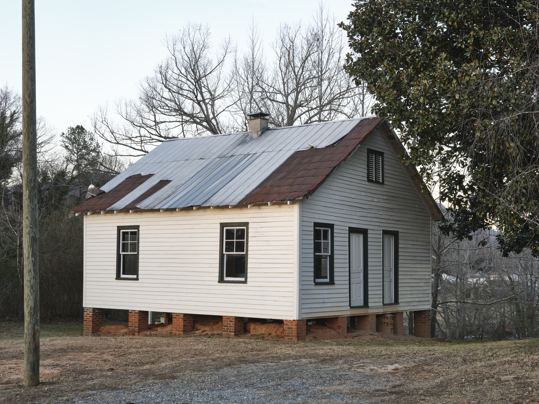 white house with a roof that has been repaired with metal