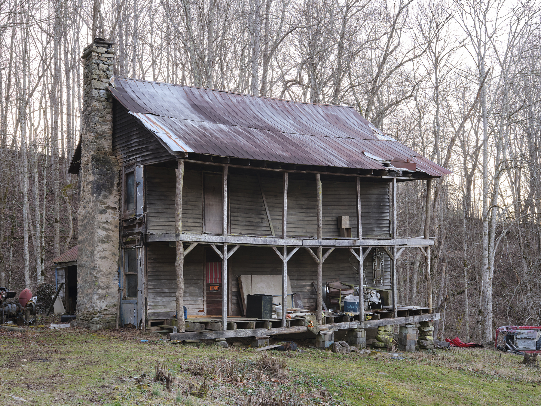 dilapidated log cabin house with keep out sign