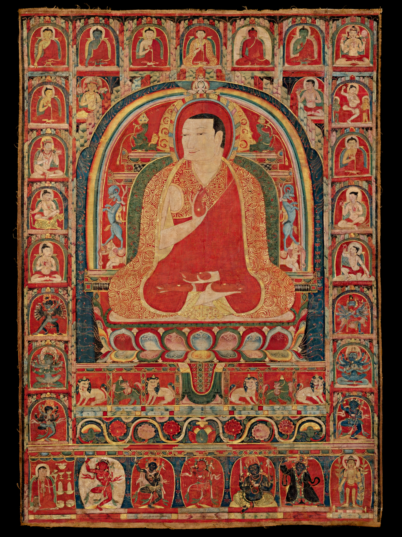 The Abbot is depicted seated in the lotus position with his hands in abhaya mudra, signifying protection and overcoming fear.  