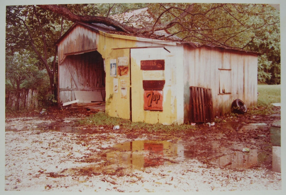 William Eggleston, Untitled (Yellow Garage with Limb on Roof Red 7-Up Sign), 1972