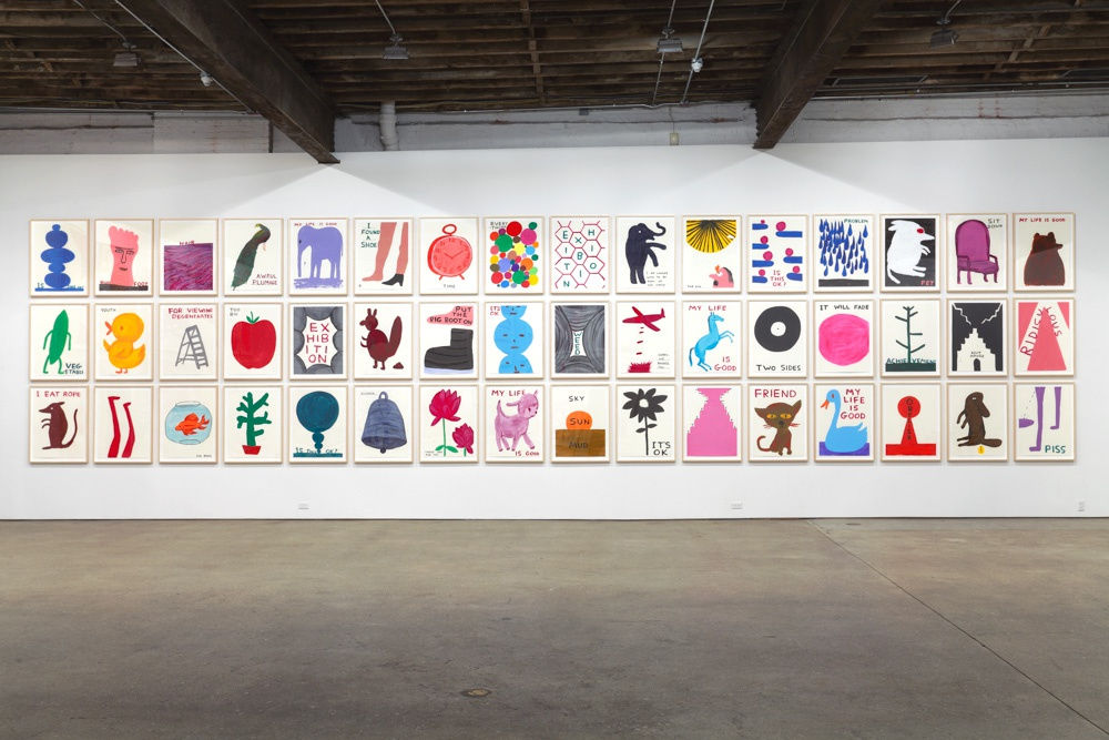 Installation view of David Shrigley's sixth solo show at Anton Kern Gallery, featuring 78 new drawings, two sculptures, an animation, and some humor. Entire wall of paintings.