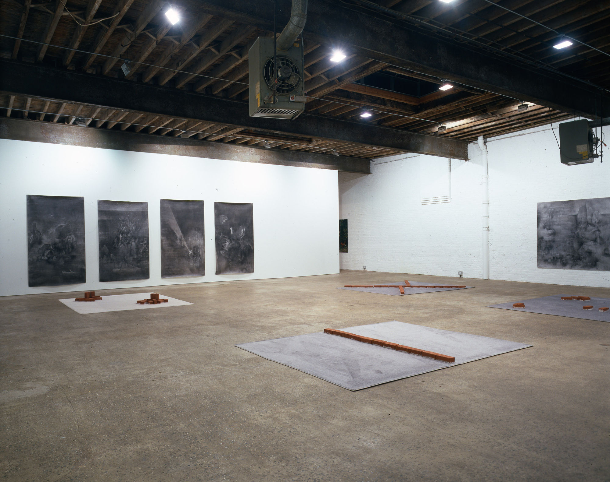 Installation view of the collaborative show featuring brick works by Georg Herold and charcoal drawings by Matthew Monahan.