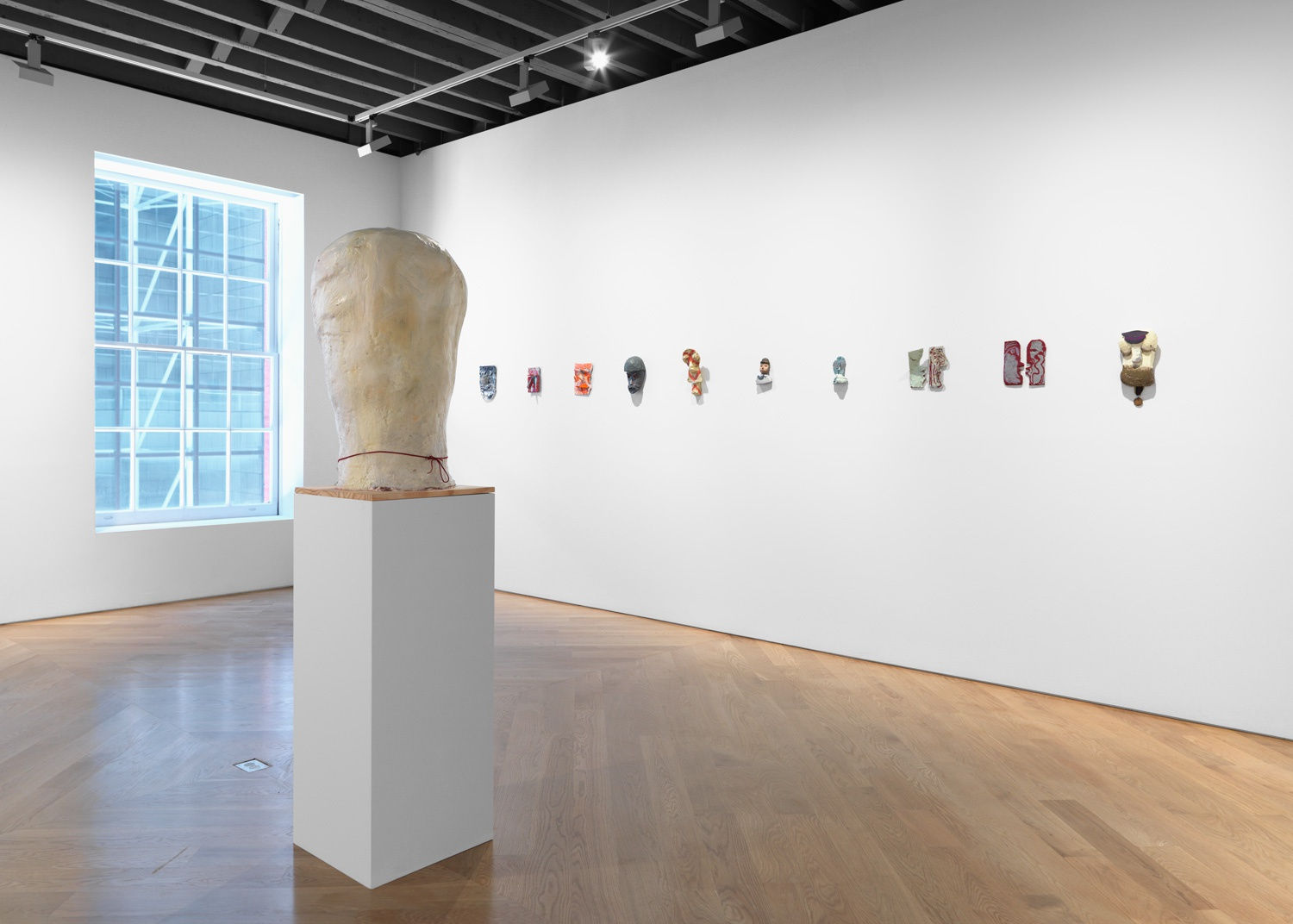 Installation view of Nicole Eisenmen show titled Faces featuring large sculptures and cast faces. Sculpture and faces featured in this photo.