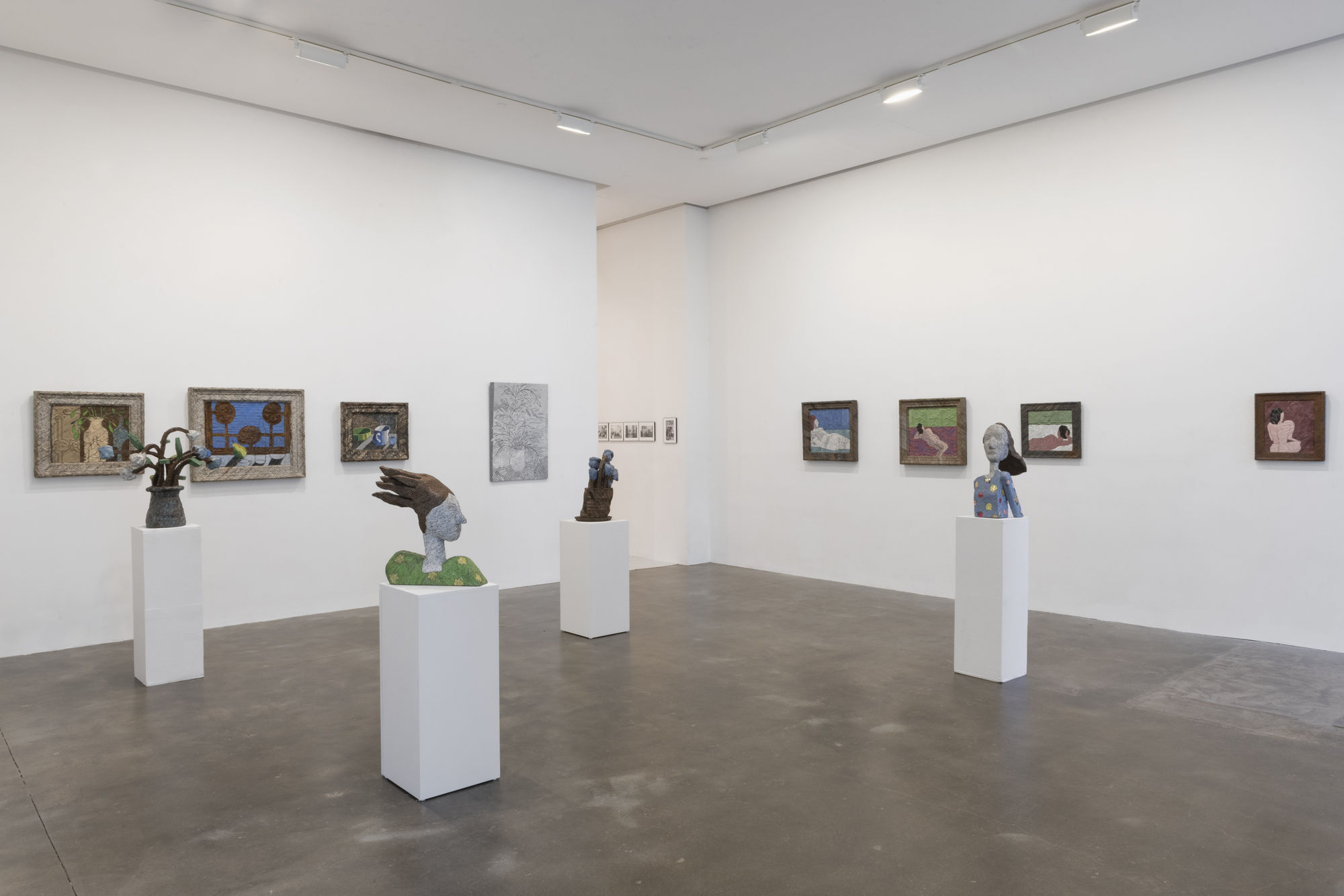 Installation view of Susan Inglett Gallery with two-dimensional works hanging on the walls and sculptures on columns 