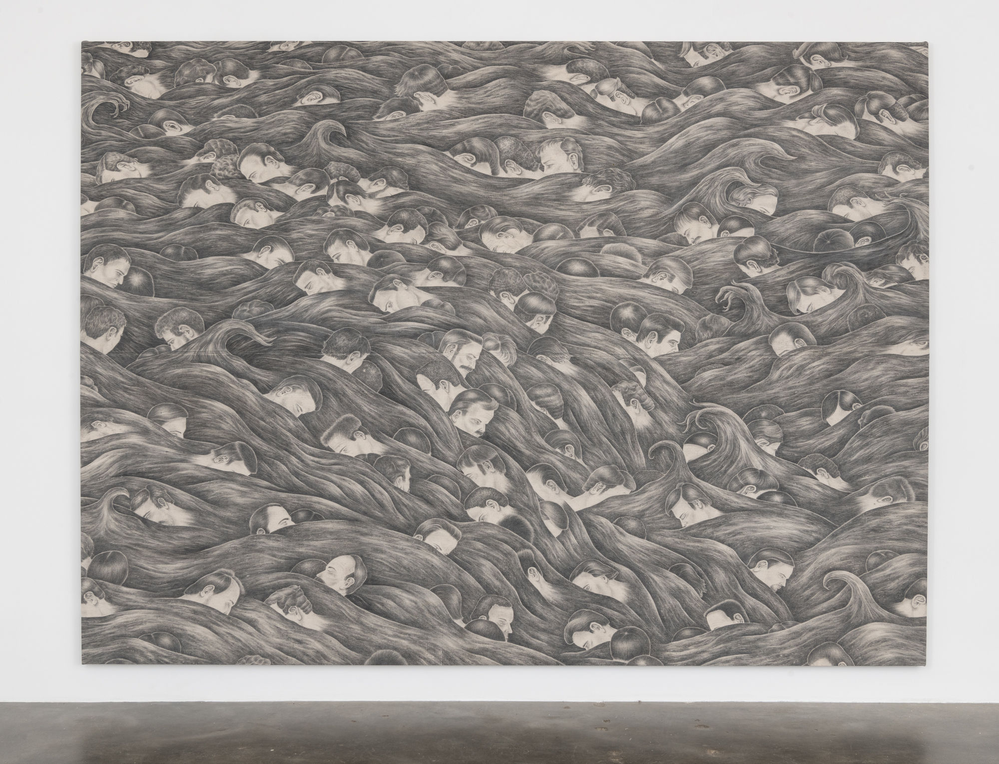 Installation view of a large graphite on canvas drawing of over a hundred male heads with light complexions sinking in waves