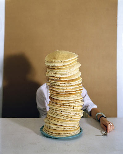 Image of a man behind a huge stack of pancakes
