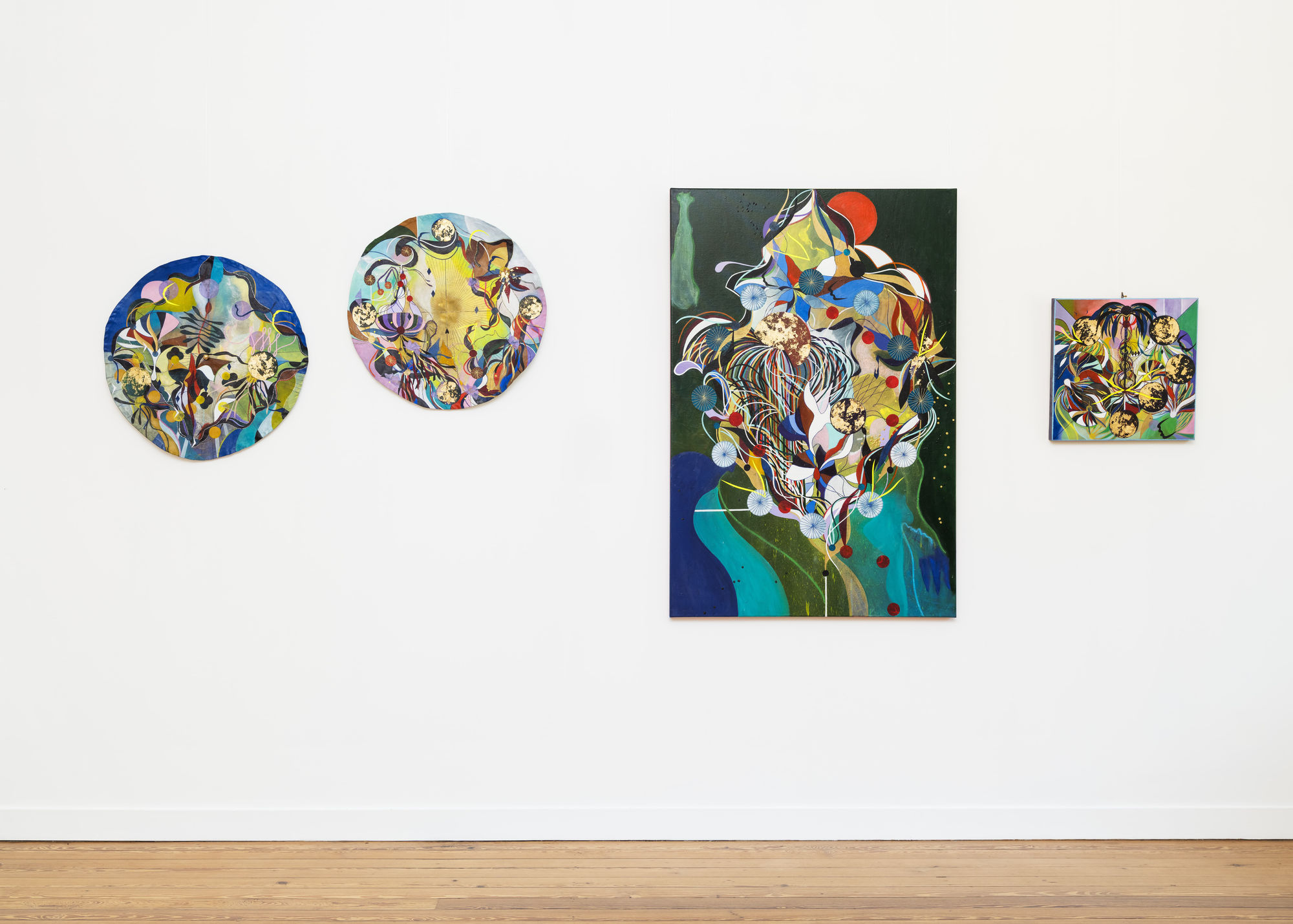 Installation view of mixed-media artworks by Tiffanie Delune in the exhibition “Alchemical Gestures” at Galerie REVEL, featuring vibrant dreamlike compositions combining celestial forms, plants, and symbols.