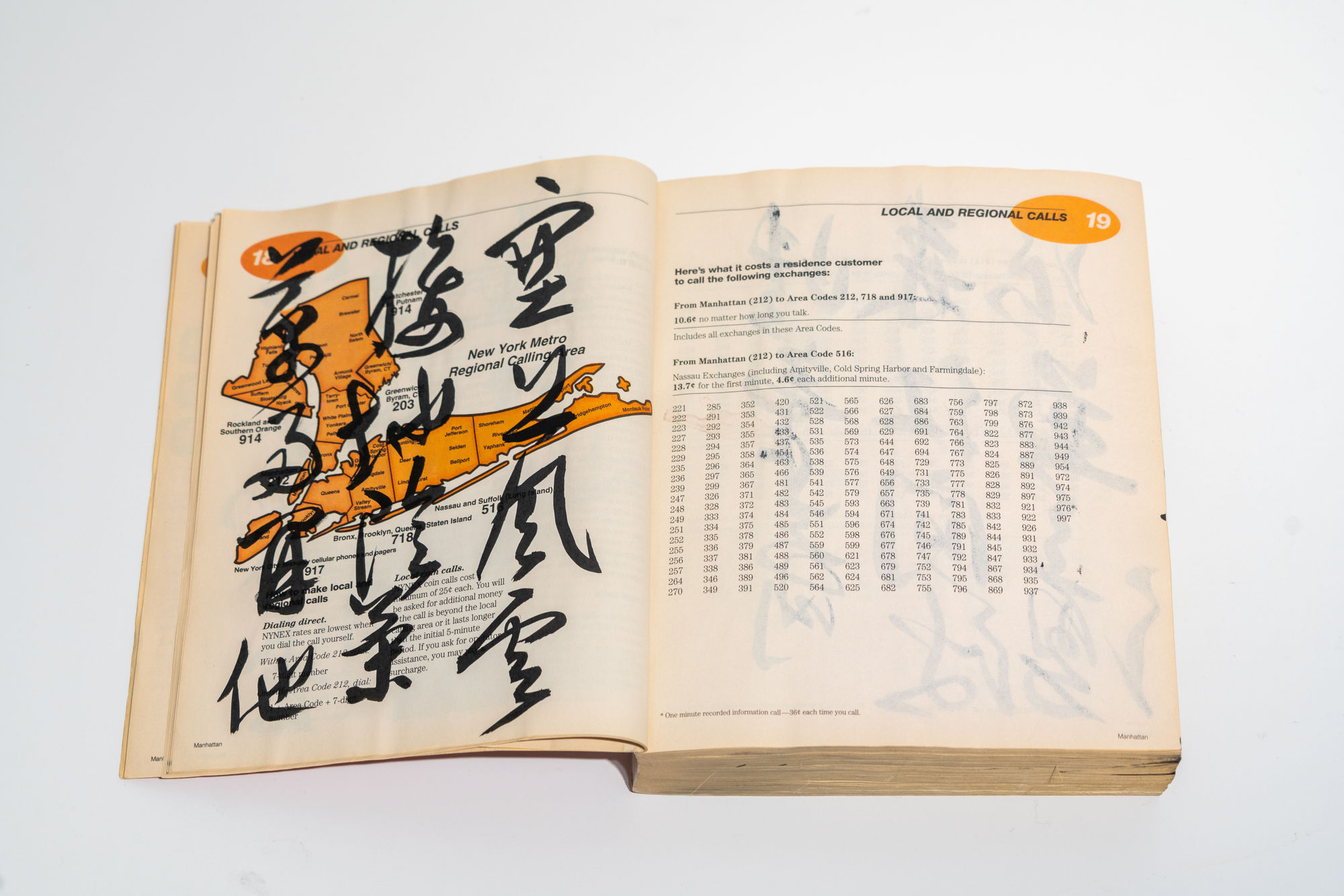 Chinese calligraphy written over the text of a page of a Manhattan White Pages book