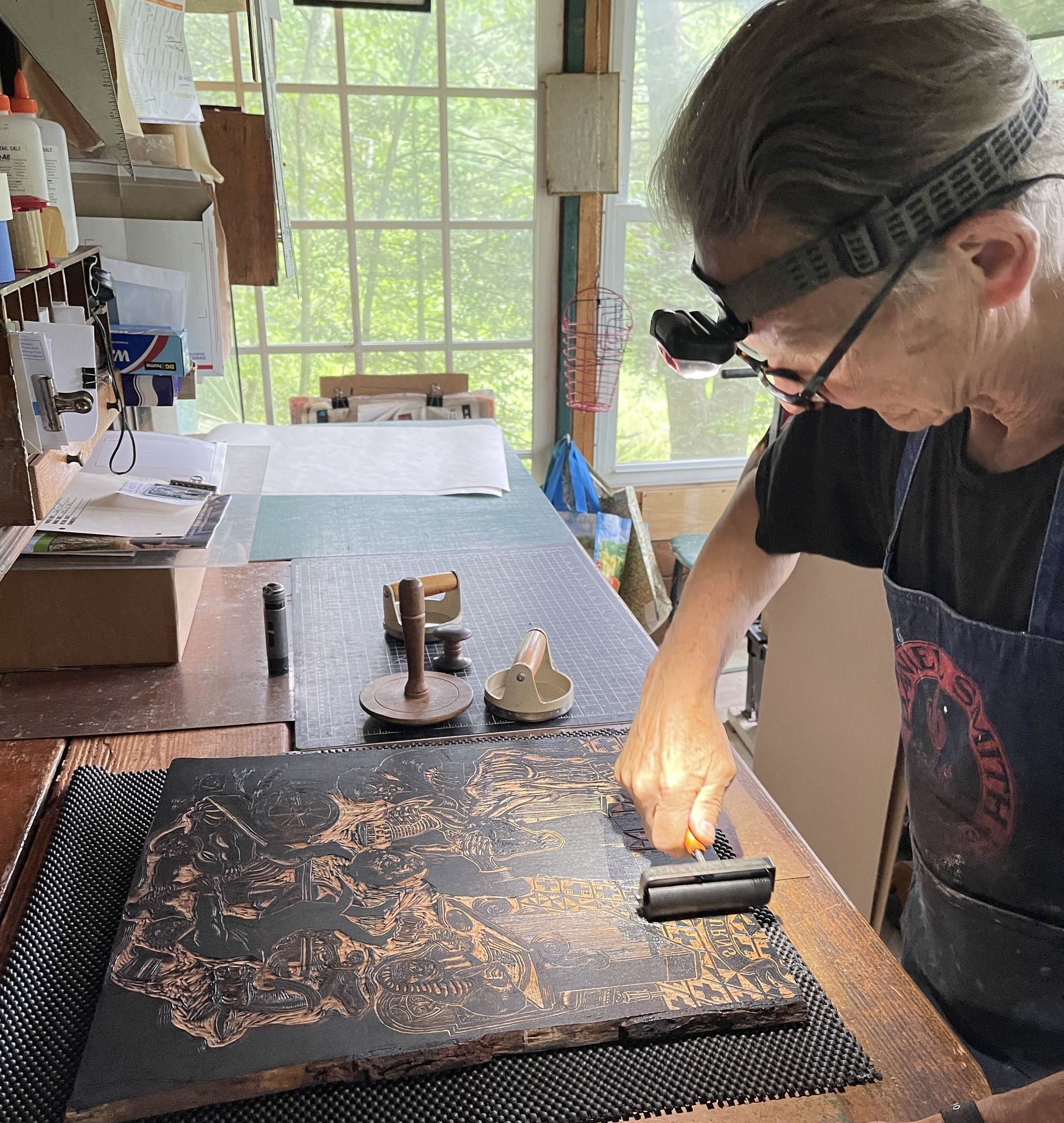 Photograph of printmaker Steve Murray inking the woodblock for a new Sue Coe print, The Martin Act, 2022