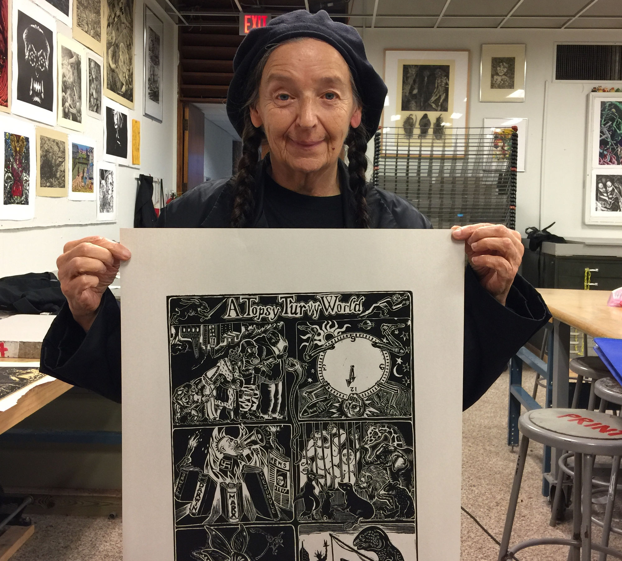 The artist holds up a linocut print created at the university's print shop