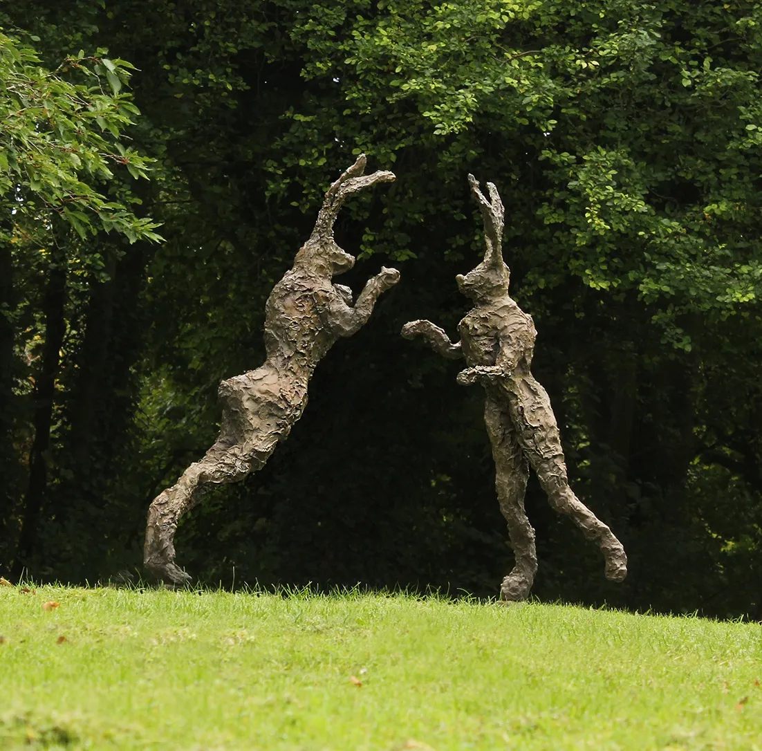 Bronze boxing hares in a garden setting