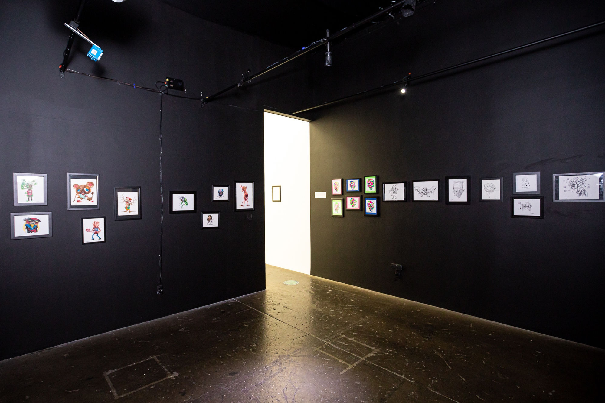 works by Alex Pardee hung on black walls