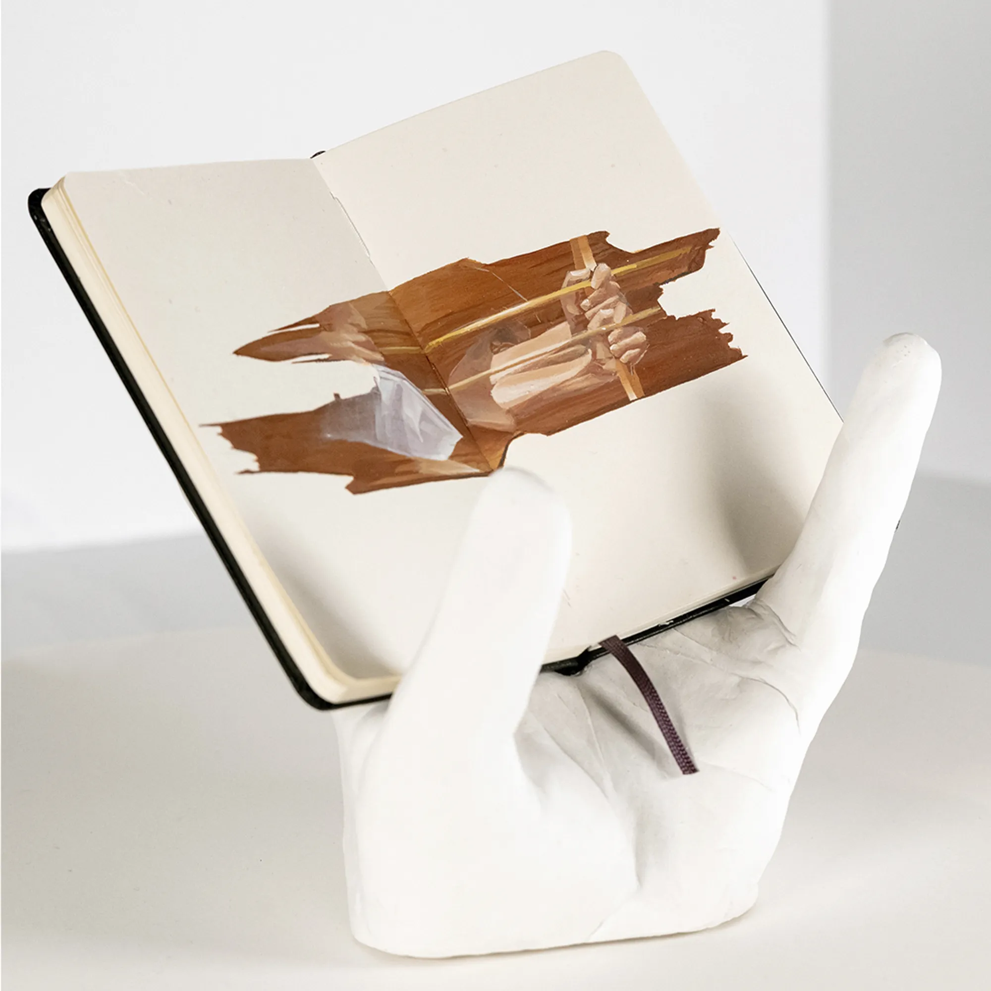 earth tone drawing in a notebook held up by a hand