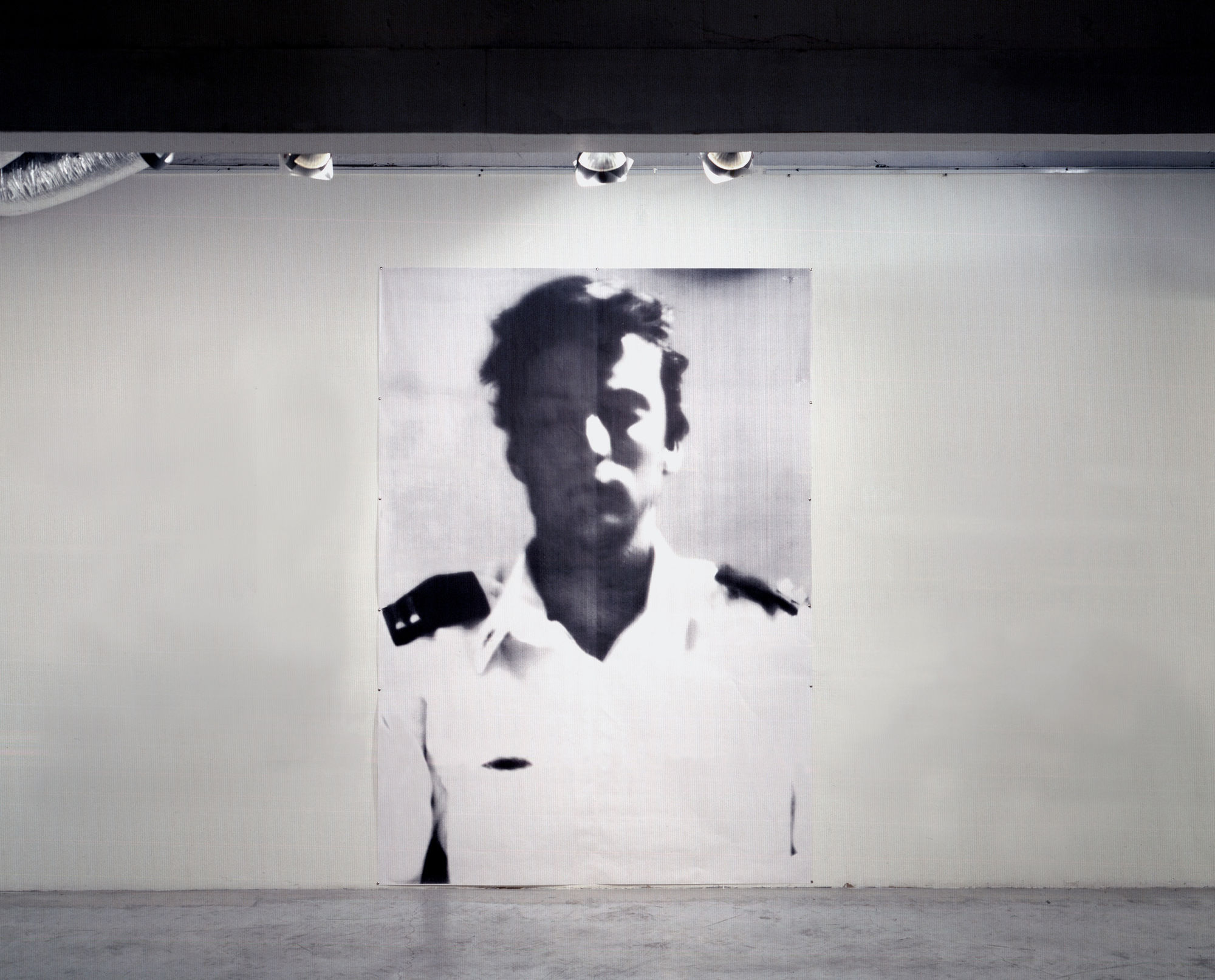 Ariel Yannay | Exhibition view: Self Portrait as a Soldier | Large-scale photographic portrait installation showing a soldier in a white uniform with high-contrast lighting.