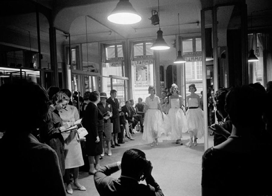 Black and white photograph of three models walking in a fashion show at the House of Chanel in Paris