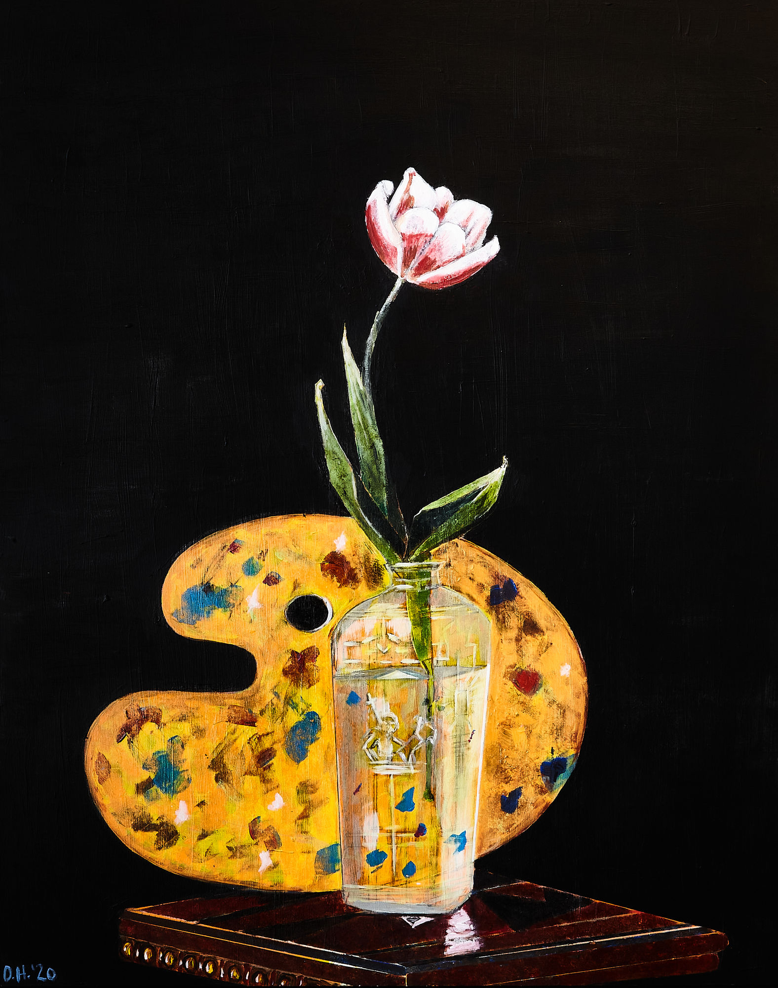 a tulip in a vase on a book in front of a painter's palette