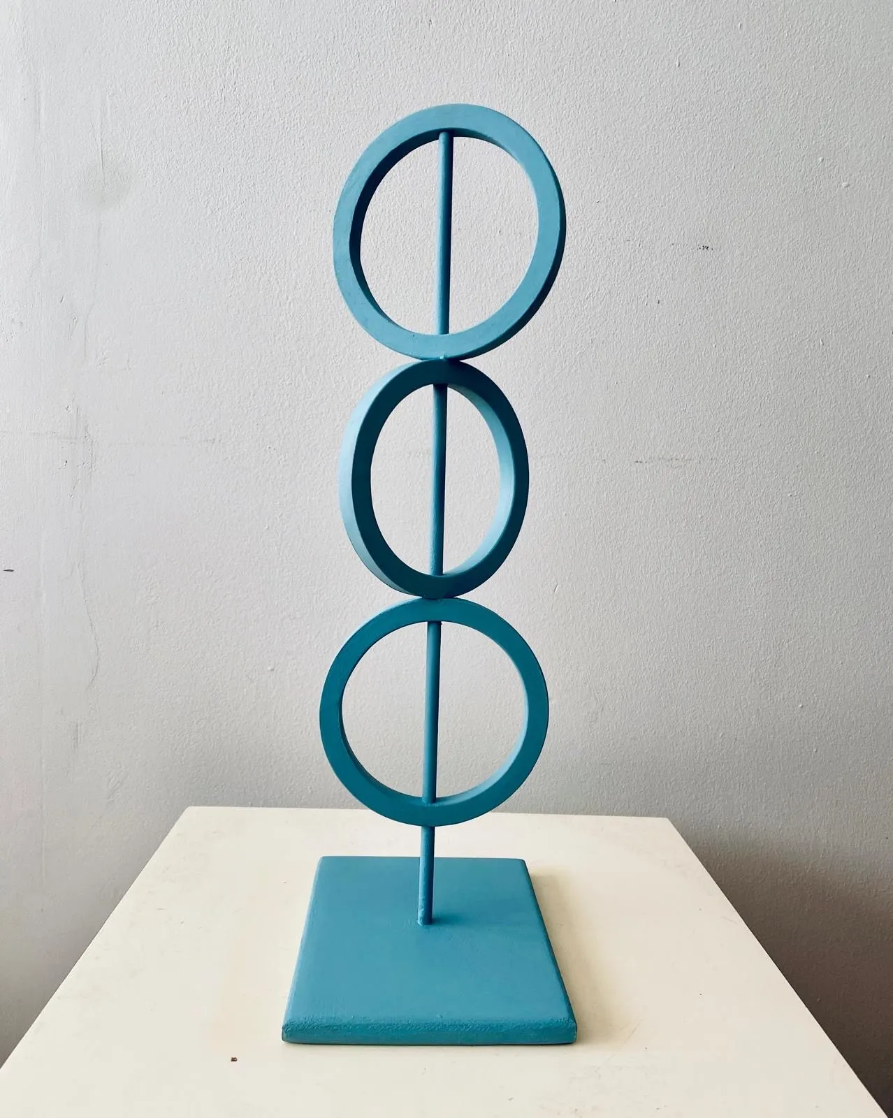 blue steel sculpture with three rings on top of each other representing Mind Body and Spirit.