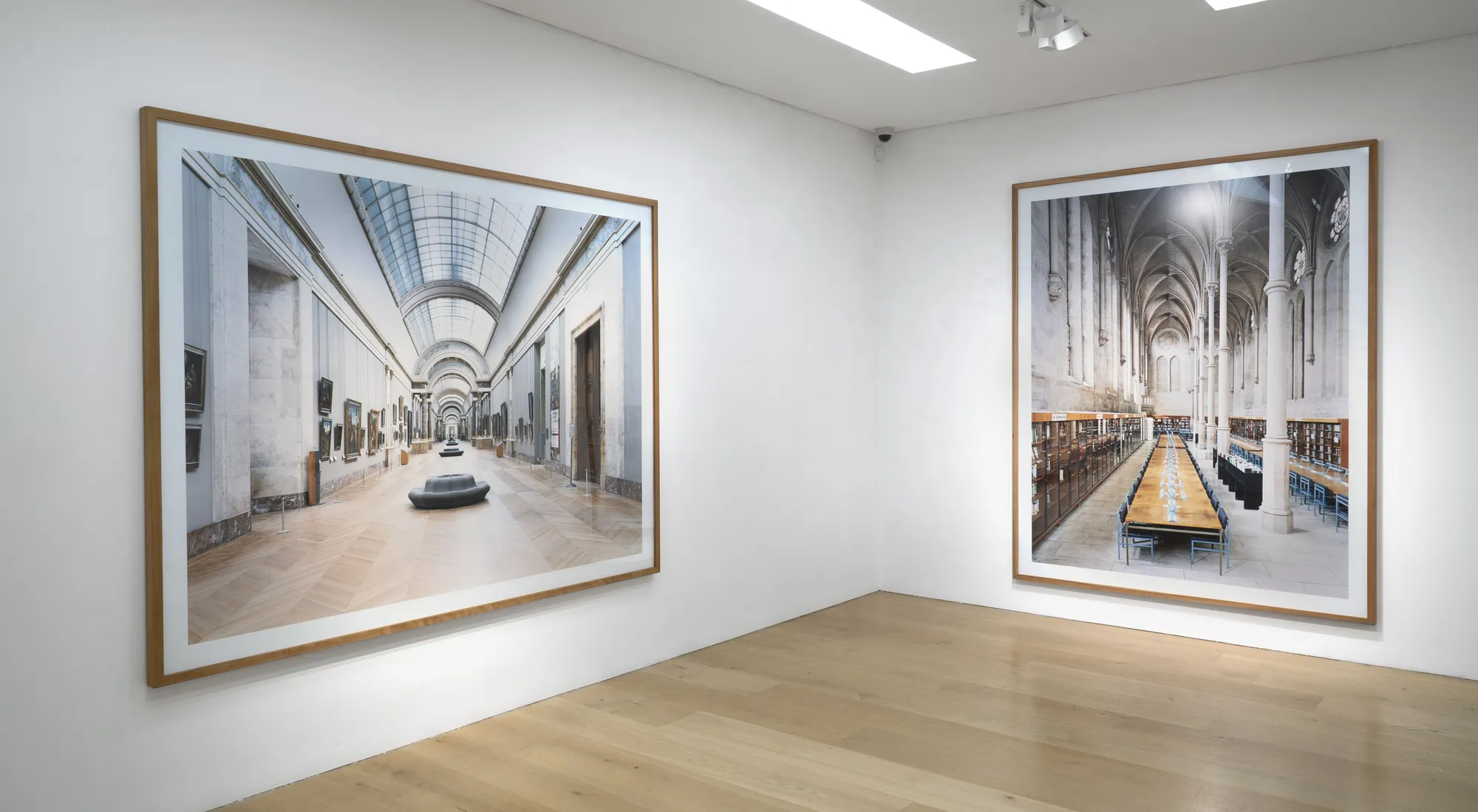 Installation view of a white cube gallery with wooden floors showing large scale framed photographs of interiors by Candida Hofer