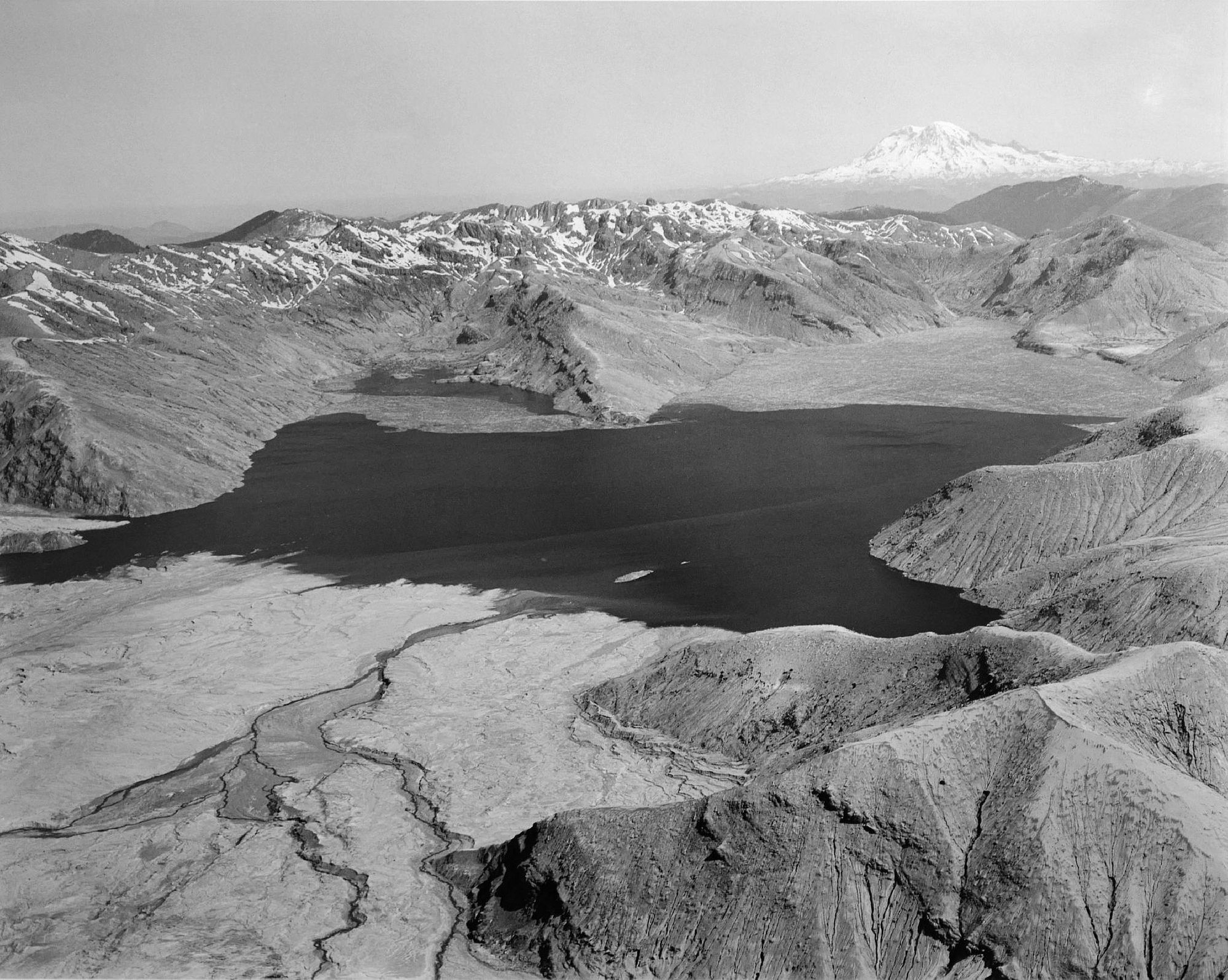 Frank Gohlke - Aerial view: Spirit Lake from the South, Mt. Rainier on horizon, 50 miles away (North end of lake filled with logs from eruption), 1982