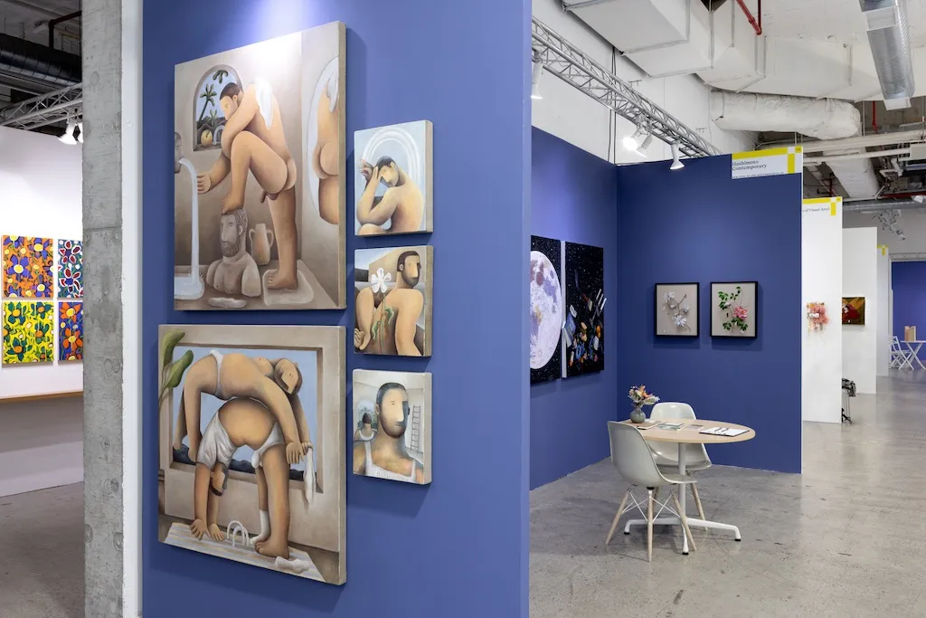 blue booth with various artworks hanging on walls. round table to the right