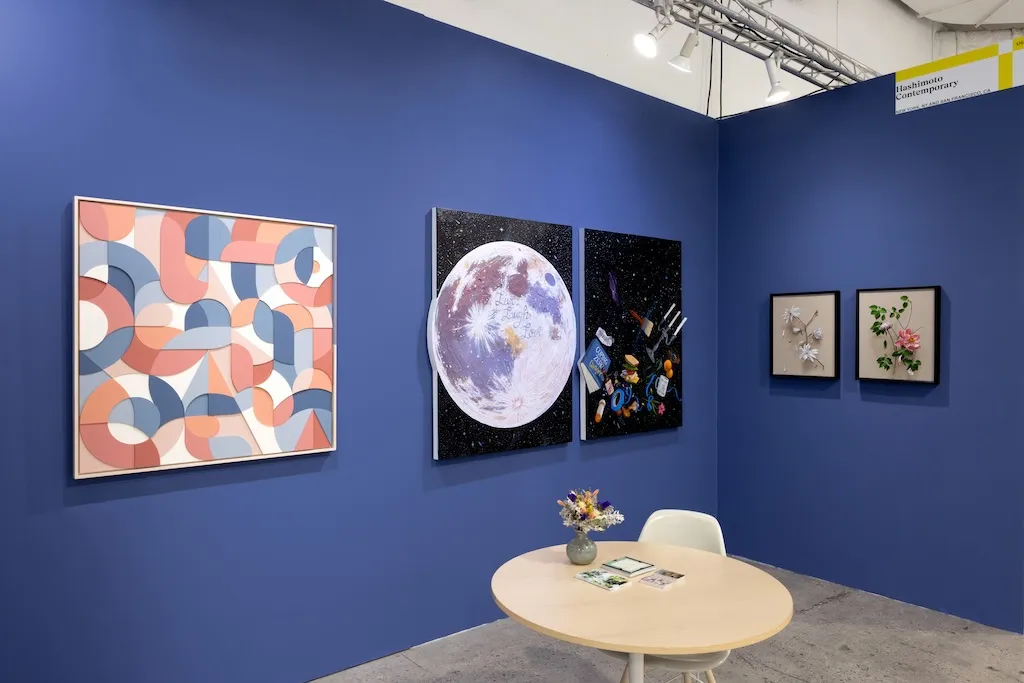 blue booth with various artworks hanging on walls. round table to the right