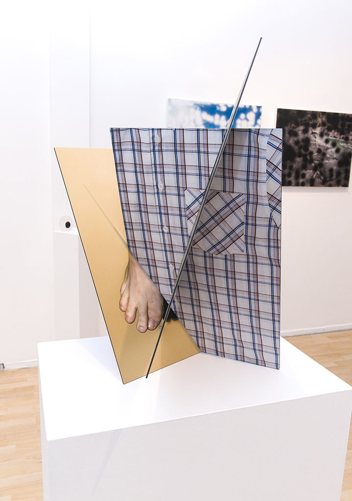 Exhibition installation view featuring abstracted sculptural work in foreground, paintings in background