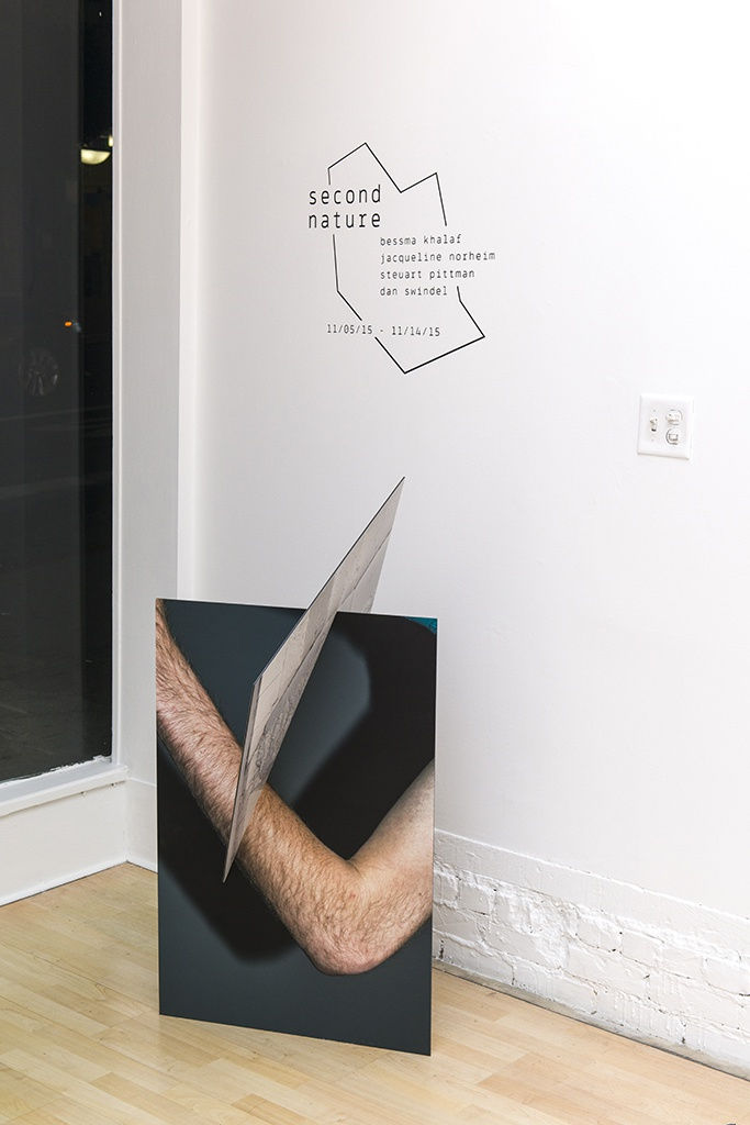 Exhibition installation view featuring abstracted sculptural work in foreground, paintings in background