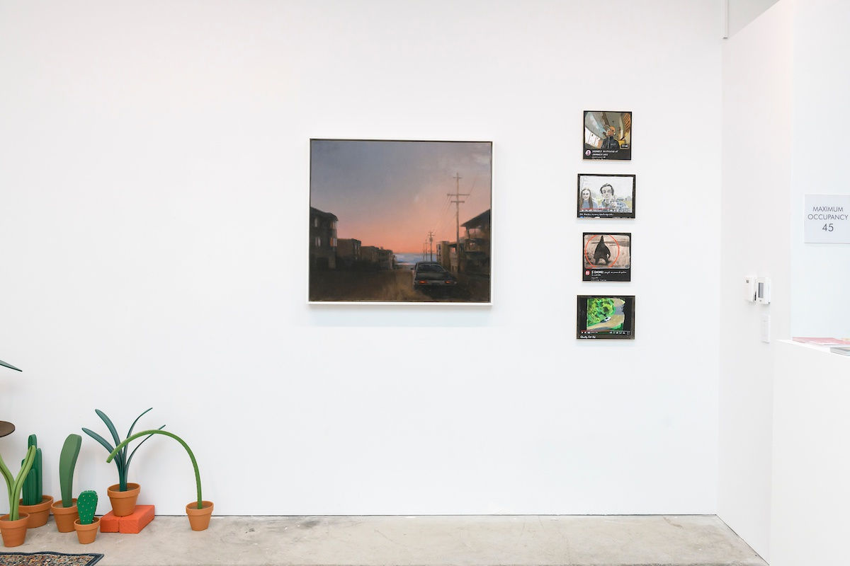 Photo of paintings hanging on a white wall and sculptures of potted plants in a gallery